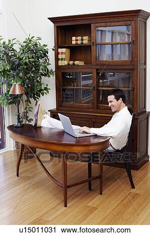 Stock Image - Side profile of a mature man using a laptop and smiling. Fotosearch