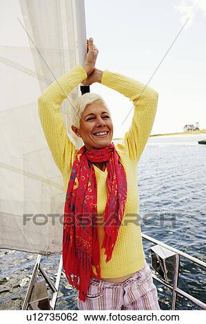 Close-up of a mature woman standing in a sailboat and smiling View Large Photo Image Stock Image - Close-up of a mature woman standing in a sailboat and smiling. Fotosearch