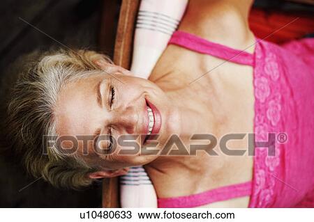 Stock Image - High angle view of a mature woman smiling with her eyes closed. Fotosearch