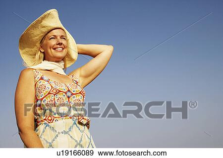 Low angle view of a mature woman looking away and smiling View Large Photo Image Stock Photo - Low angle view of a mature woman looking away and smiling. Fotosearch