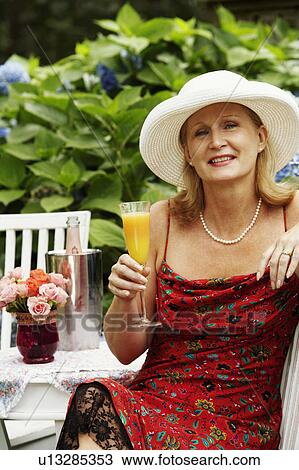 Stock Image - Portrait of a mature woman holding a glass of juice. Fotosearch