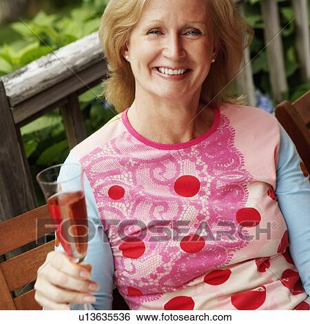 Portrait of a mature woman holding a champagne flute View Large Photo Image Stock Photograph - Portrait of a mature woman holding a champagne flute. Fotosearch