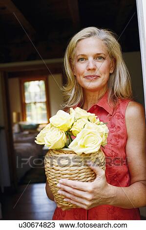 Portrait of a mature woman holding flowers in a vase View Large Photo Image Stock Image - Portrait of a mature woman holding flowers in a vase. Fotosearch