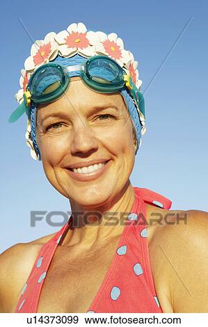 Stock Photo - Portrait of a mature woman leaning against a fence and smiling. Fotosearch