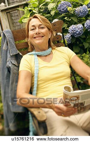 Stock Photograph - Portrait of a mature woman sitting in an armchair and smiling. Fotosearch