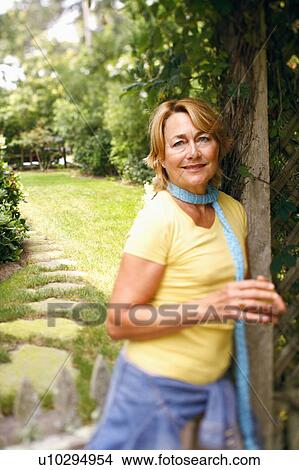 Portrait of a mature woman standing and smiling in a park View Large Photo Image Picture - Portrait of a mature woman standing and smiling in a park. Fotosearch