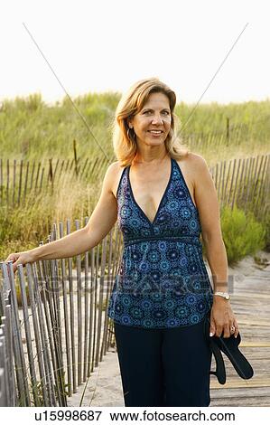 Stock Photo - Portrait of a mature woman standing near a fence. Fotosearch