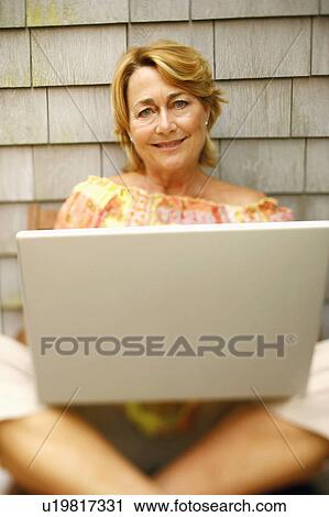 Portrait of a mature woman using a laptop and smiling View Large Photo Image Stock Image - Portrait of a mature woman using a laptop and smiling. Fotosearch
