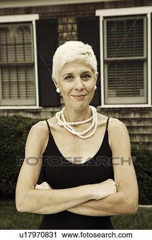 Stock Image - Portrait of a senior woman standing with her arms crossed. Fotosearch