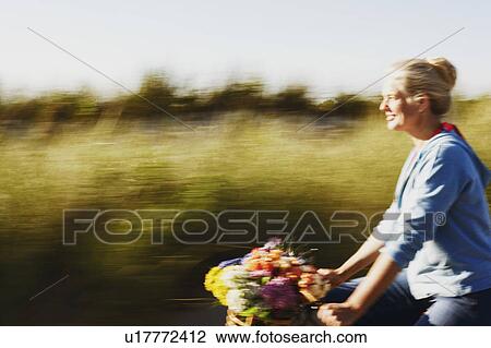 Stock Image - Side profile of a mature woman riding a bicycle. Fotosearch