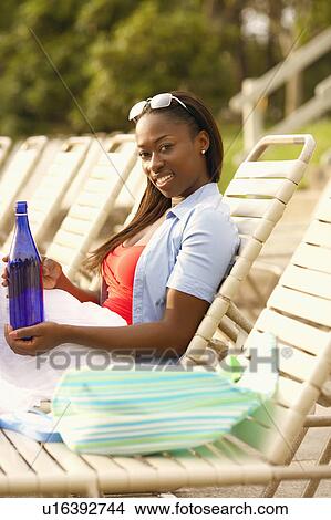 Side profile of a mid adult woman reclining on a lounge chair View Large Photo Image Picture - Side profile of a mid adult woman reclining on a lounge chair. Fotosearch