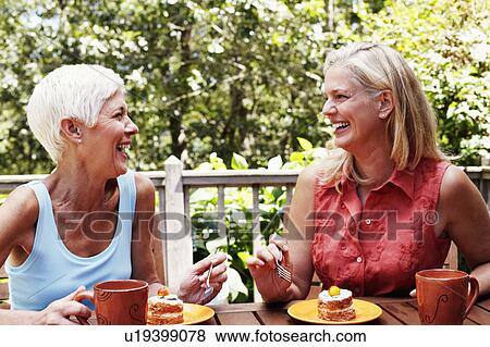 Two mature women sitting at the table with plates of dessert in front of them and smiling View Large Photo Image Stock Photo - Two mature women sitting at the table with plates of dessert in front of them and smiling. Fotosearch
