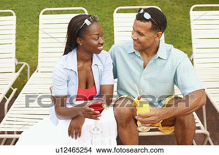 Mature man holding a glass of juice with a mid adult woman holding a martini glass View Large Photo Image Picture - Mature man holding a glass of juice with a mid adult woman holding a martini glass. Fotosearch