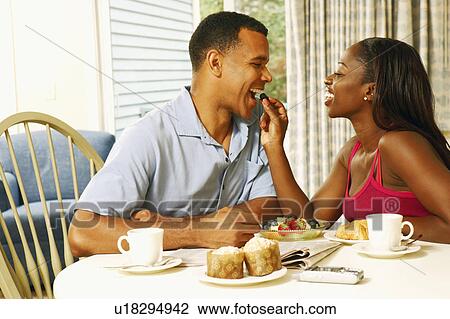 Mid adult woman feeding fruit to a mature man at a breakfast table View Large Photo Image Stock Image - Mid adult woman feeding fruit to a mature man at a breakfast table. Fotosearch