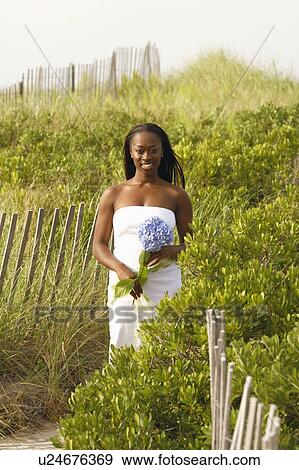 Stock Photo - Portrait of a mid adult woman holding a flower and smiling. Fotosearch