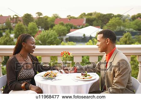 Side profile of a couple sitting at a table and smiling View Large Photo Image Stock Photo - Side profile of a couple sitting at a table and smiling. Fotosearch