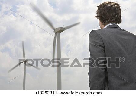 Stock Image - Businessman looking at wind turbines. Fotosearch