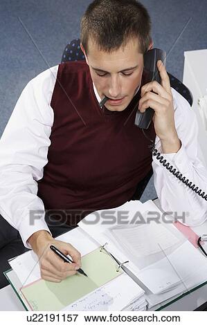 Stock Photo - Businessman on phone, writing. Fotosearch