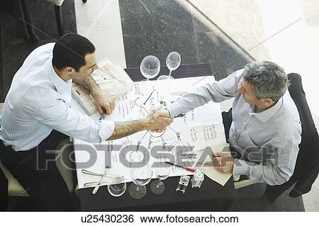 Stock Photograph - Businessmen shaking hand in restaurant . Fotosearch