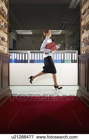 Stock Photo - Businesswoman in a hallway with binders . Fotosearch