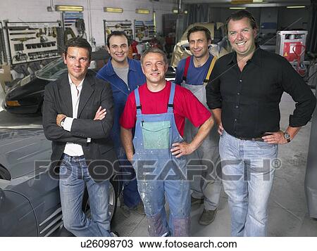 Stock Image - Group of workers and bosses in a garage.. Fotosearch