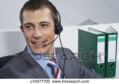 Stock Image - Man with headset, smiling, portrait. Fotosearch