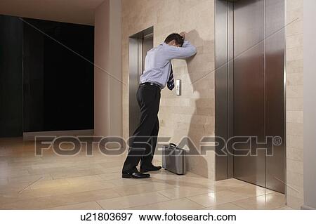 Stock Photo - Man with his head down leaning against wall. Fotosearch