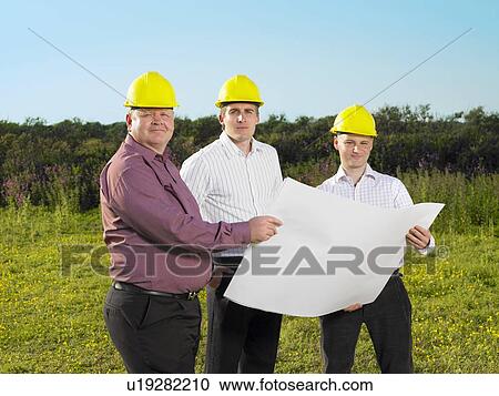 Stock Image - Three surveyors on a field.. Fotosearch
