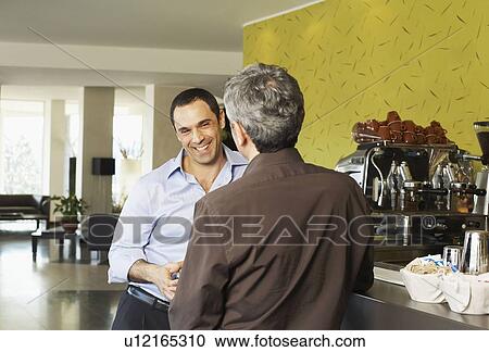 Stock Image - Two males enjoying a drink at bar. Fotosearch