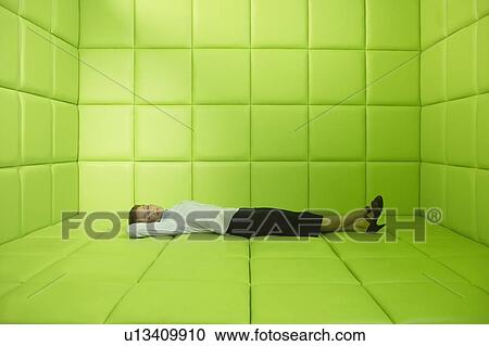 Stock Image - Woman lying in green padded cell. Fotosearch