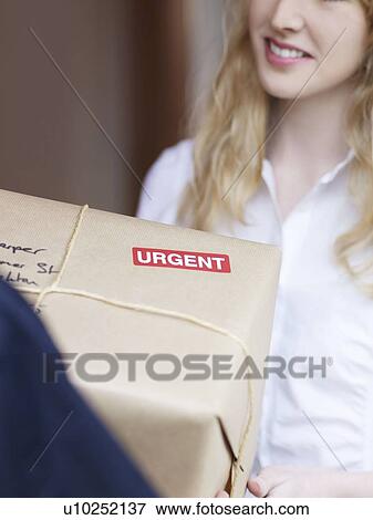 Stock Photo - Woman signing for urgent delivery. Fotosearch