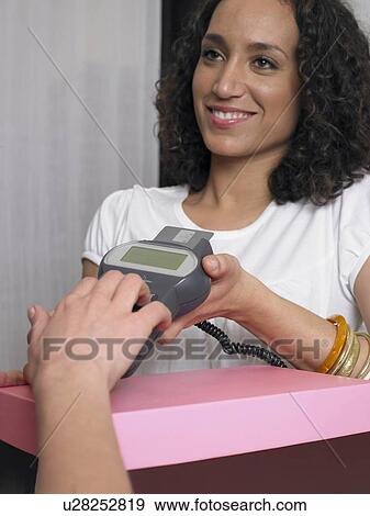 Young woman holding credit card reader for customer, smiling View Large Photo Image Stock Photo - Young woman holding credit card reader for customer, smiling. Fotosearch