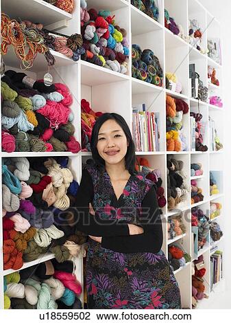 Young woman leaning on shelves of wool in craft shop, smiling View Large Photo Image Stock Image - Young woman leaning on shelves of wool in craft shop, smiling. Fotosearch