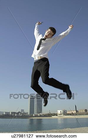 Business man jumping by seafront View Large Photo Image Stock Photo - Business man jumping by seafront. Fotosearch