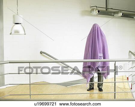 Stock Image - Businessman standing under a blanket. Fotosearch