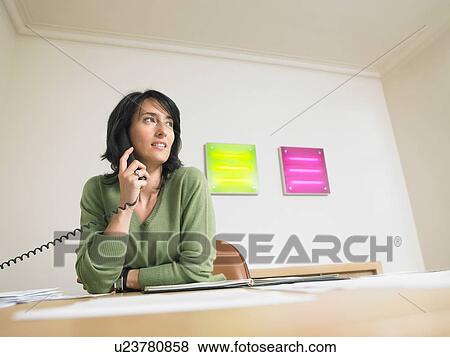 Stock Photo - Businesswoman at her desk giving a call.. Fotosearch