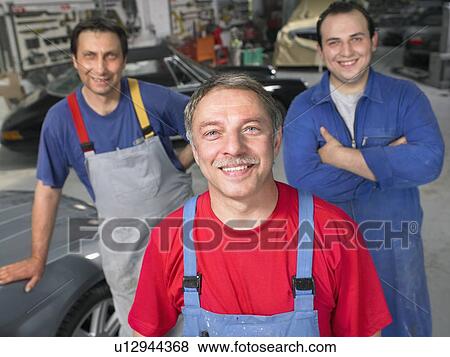 Stock Photo - Three workers in a garage portrait.. Fotosearch