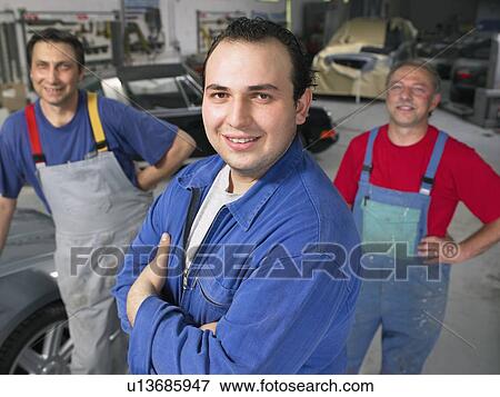 Stock Photo - Three workers in a garage portrait.. Fotosearch