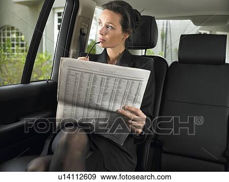 Stock Photo - Woman in car, reading newspaper. Fotosearch