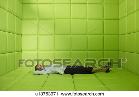 Stock Image - Woman lying in green padded cell. Fotosearch