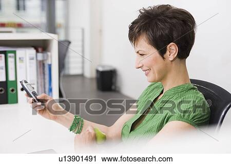 Woman text messaging at work View Large Photo Image Stock Image - Woman text messaging at work. Fotosearch
