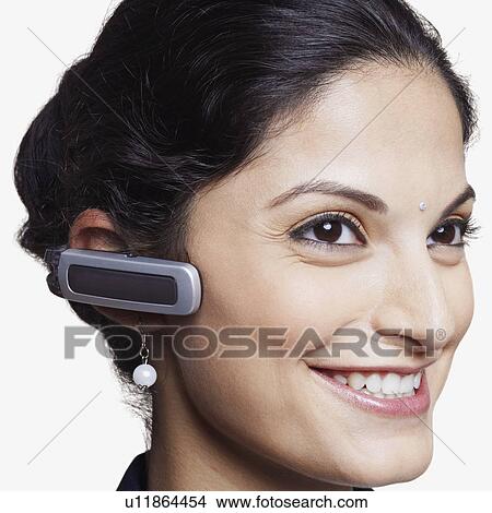 Close-up of a businesswoman wearing a hands free device and smiling View Large Photo Image Picture - Close-up of a businesswoman wearing a hands free device and smiling. Fotosearch