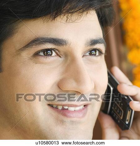 Stock Image - Close-up of a young man talking on a mobile phone. Fotosearch