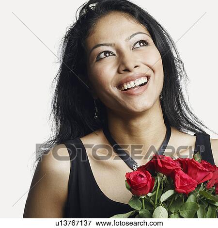 Stock Photo - Close-up of a young woman holding a bouquet of roses and smiling. Fotosearch