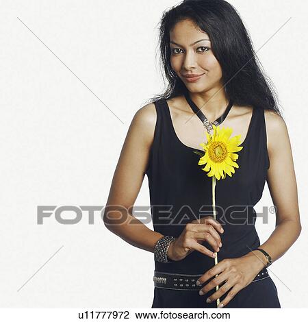 Stock Image - Portrait of a mid adult woman holding a sunflower. Fotosearch
