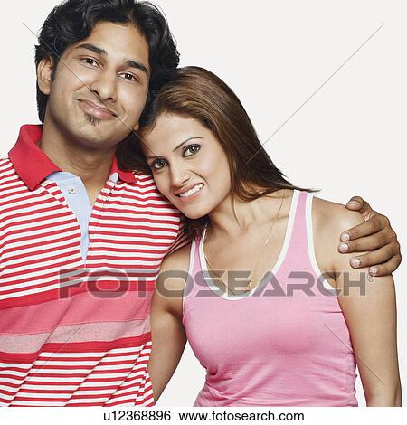 Stock Photograph - Portrait of a young couple standing and smiling. Fotosearch