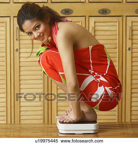 Portrait of a young woman crouching on a weighting scale and smiling View Large Photo Image Stock Photography - Portrait of a young woman crouching on a weighting scale and smiling. Fotosearch