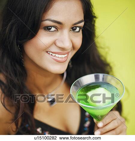 Stock Image - Portrait of a young woman holding a glass of cocktail. Fotosearch