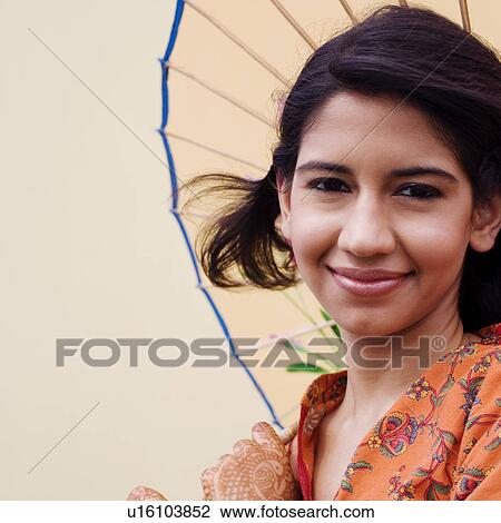 Stock Image - Portrait of a young woman holding a parasol and grinning. Fotosearch