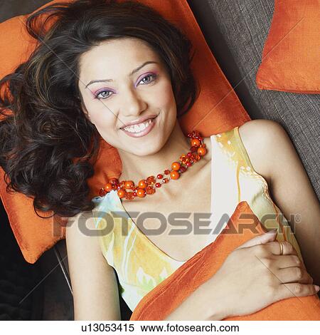 Stock Photography - Portrait of a young woman lying on a couch and smiling. Fotosearch